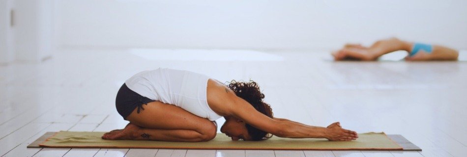 Mujer practicando Ashtanga Yoga en postura de Balasana durante clase individualizada en estilo Mysore